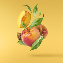 Flying fresh ripe peach with green leaves isolated