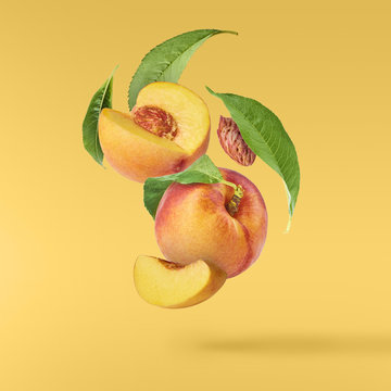 Flying fresh ripe peach with green leaves isolated