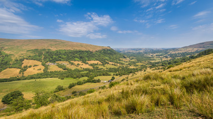 Fototapeta premium Typical landscape of Brecon Beacons National Park with mountians, trees and hedges along the small roads.
