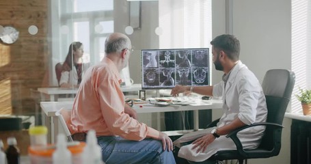 Doctor and patient look at computer results examination.Doctor tells about results of treatment, showing picture on computer. Institute of human brain