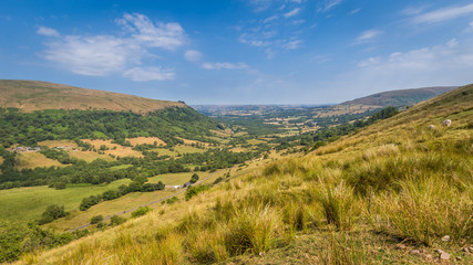 Fototapeta premium Typical landscape of Brecon Beacons National Park with mountians, trees and hedges along the small roads.
