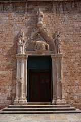 Fototapeta na wymiar Croatia - entrance to the Franciscan church in Dubrovnik with a beautiful portal from 1498 showing the pie - Mother of God with the body of Christ in her lap.