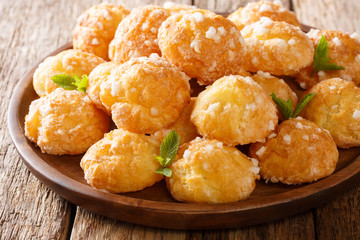 French heap Cream Puffs choux with pearl sugar and mint macro on a plate on a table. Horizontal