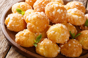 Chouquettes French Cream Puffs dessert is decorated with pearl sugar and mint closeup. Horizontal