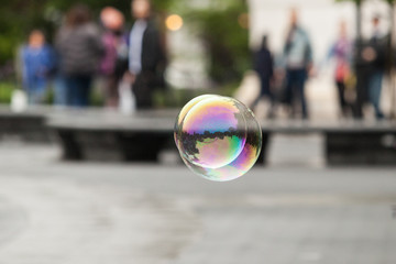 two flying soap bubbles in the city with unfocus people in the background