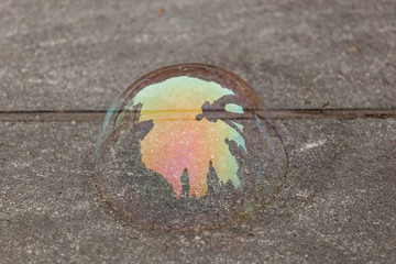 colorful soap bubble on stone street with reflection of people