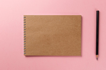 Notepad and pencil on pink background. Top view with copy space. Flat lay. Pastel background. Back to school and education concept