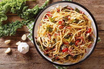 Italian lunch of pasta with cabbage kale, bacon, tomatoes and parmesan closeup. Horizontal top view