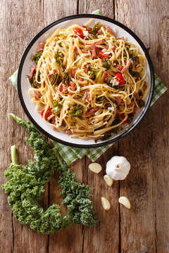 Italian food: pasta linguine with fried bacon, vegetables and parmesan cheese close-up on a plate. Vertical top view