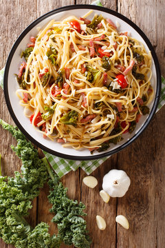 Italian lunch of pasta with cabbage kale, bacon, tomatoes and parmesan closeup. Vertical top view