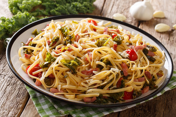 Italian food: pasta linguine with fried bacon, vegetables and parmesan cheese close-up on a plate on a table. horizontal