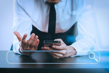 close up of businessman working with smart phone on wooden desk in modern office