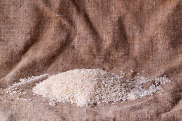 Raw rice is scattered on sackcloth. Uncooked food. selective focus