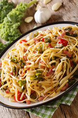 pasta Linguine with cabbage kale, bacon, tomatoes and parmesan close-up on a plate. vertical