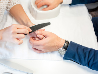 Man gets his nails done. Hands closeup