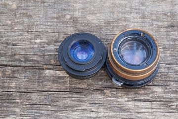 close up photo of old camera lens over wooden table. image is retro filtered. selective focus
