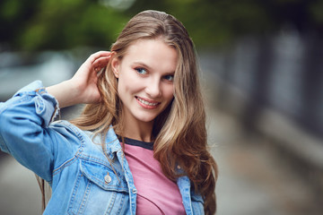 A blond happy girl smiles in an urban style. Portrait of a young woman.