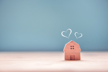 Home sweet home, house wood with heart shape on wooden and blue background, copy space.