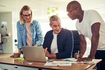 Smiling diverse businesspeople using a laptop together in an off