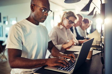 Young African designer working online with colleagues in the bac