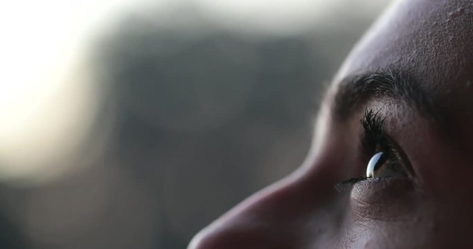 Young woman face opening eyes in meditation and contemplation loooking up at the sky with hope and faith