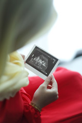 A mother looking at sonogram print of her baby.