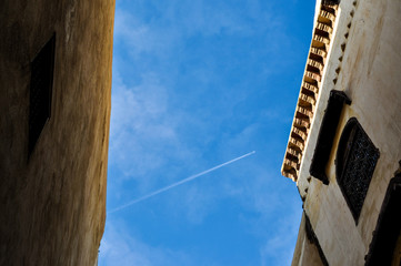 Plane trail crossing through old buildings