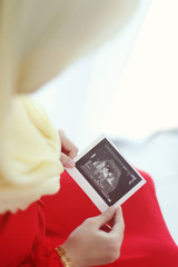 A mother looking at sonogram print of her baby.