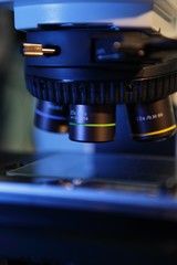 Close up of microscope lenses focused on a specimen in blue light