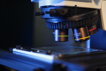 Close up of microscope lenses focused on a specimen in blue light