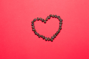 Grains of coffee in the form of heart on a red background