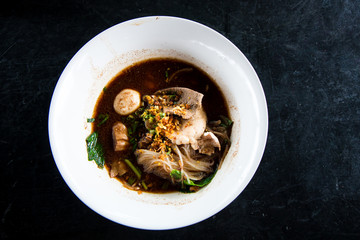 Thai Noodles Soup in a bowl on black table
