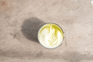 Top view of hot Matcha green tea latte on the wood table.