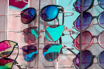 Defferent sunglasses closeup. Sale of mirror sunglasses. A market tray with sunglasses. Many different sunglasses. Sale of cheap glasses on the street.