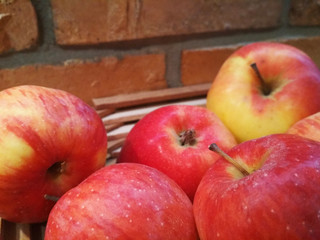 Ripe red apples on table close up, on brick wall background