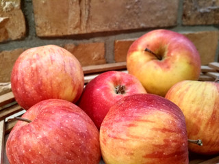 Ripe red apples on table close up, on brick wall background