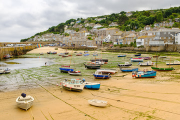 Fishing boats at low tide within Mousehole harbour, Cornwall.