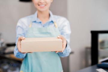 Mid section portrait of unrecognizable woman wearing apron holding box with takeaway food and...
