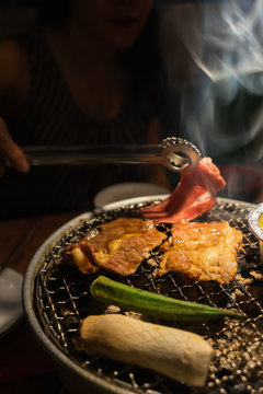 Asian woman with beef barbecue on the grill. Japanese and Korean Food concept.