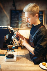 Male barista pours boiling water into the glass