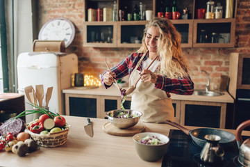 Housewife in apron cooking fresh salad on kitchen