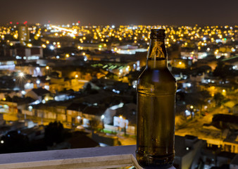 botella de cerveza con fondo de luces de ciudad