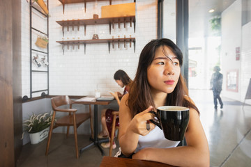 Young Asian woman enjoying coffee in cafe.