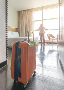Luggage in hotel guest room with traveller lifestyle of  business woman staying for work travel or vacation trip looking out the window toward city view