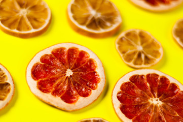 Naklejka na ściany i meble Scattered dried slices grapefruit and lemon on yellow background