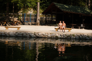 Fototapeta na wymiar Active couple rests on river bank on a hot summer day