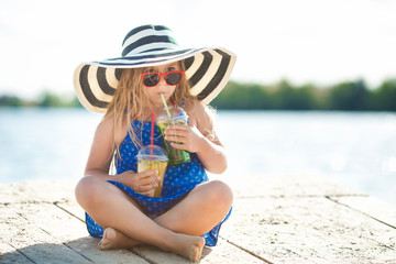 Little cute girl on the sea. Girl in the hat in summer time. Adorable child on the coastline.