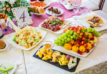 Served table at the Banquet. Fruits, snacks, delicacies and flowers in the restaurant. Solemn event or wedding.