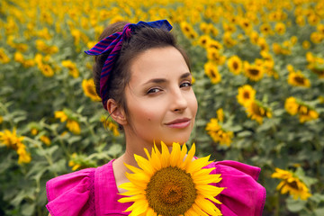 woman in a pink dress standing in the field with sunflowers