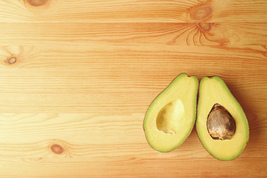 Top View of Ripe Avocados Fruit Cut In Half Isolated on Wooden background with Free Space for Text and Design 